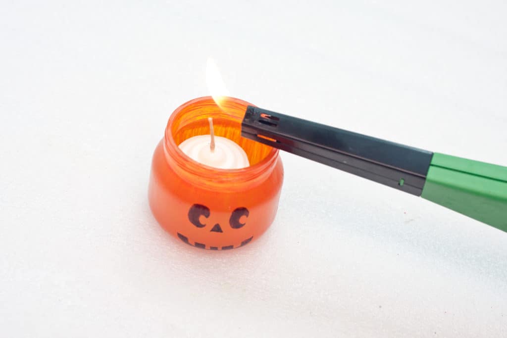 Lighting your glass jack-o-lantern jar.